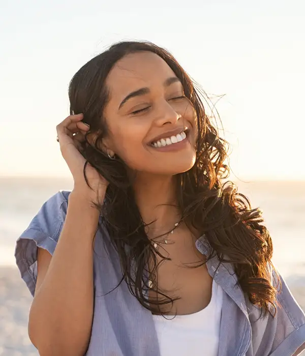 young woman with a beautiful smile and hair whipping in the wind on a beach