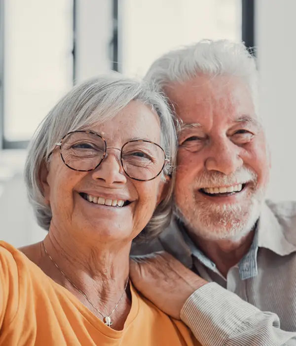 smiling mature wife and husband hugging, looking at camera