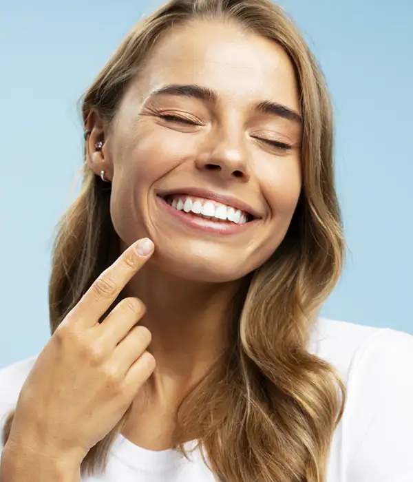 young woman pointing to her beautiful white smile