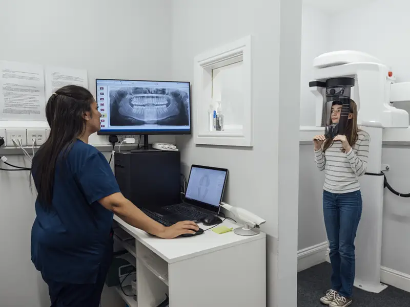 An over the shoulder wide angle view of a young teenage girl who is having dental scans taken to do some comparisons of how her teeth are progressing with her treatment